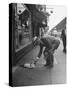 Man Bending over to Touch Cat Sitting on Sidewalk-Nina Leen-Stretched Canvas