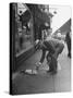 Man Bending over to Touch Cat Sitting on Sidewalk-Nina Leen-Stretched Canvas