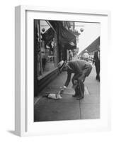 Man Bending over to Touch Cat Sitting on Sidewalk-Nina Leen-Framed Premium Photographic Print