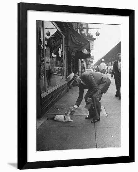 Man Bending over to Touch Cat Sitting on Sidewalk-Nina Leen-Framed Photographic Print