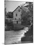 Man Fishing Beside a Waterfall and a 100 Year Old Mill-Bob Landry-Mounted Photographic Print