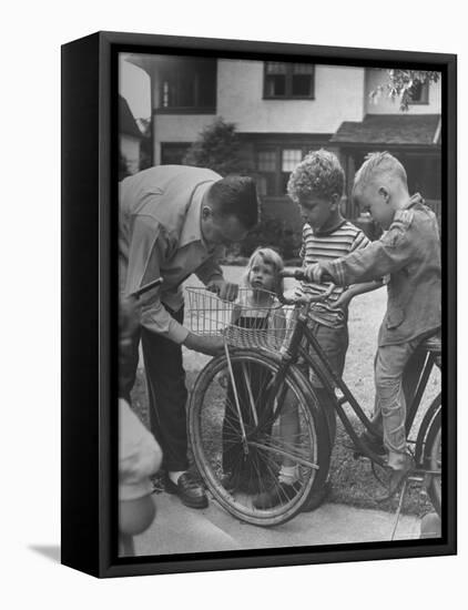 Man Fixing Basket on Bicycle as Children Watch Attentively-Nina Leen-Framed Stretched Canvas