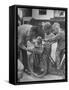 Man Fixing Basket on Bicycle as Children Watch Attentively-Nina Leen-Framed Stretched Canvas