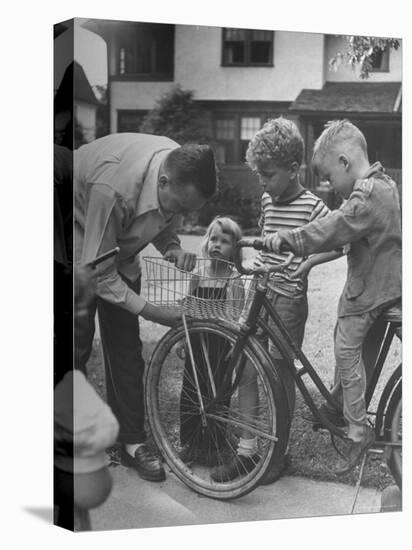 Man Fixing Basket on Bicycle as Children Watch Attentively-Nina Leen-Stretched Canvas