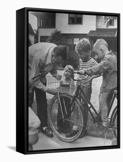 Man Fixing Basket on Bicycle as Children Watch Attentively-Nina Leen-Framed Stretched Canvas