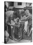 Man Fixing Basket on Bicycle as Children Watch Attentively-Nina Leen-Stretched Canvas