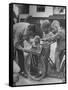 Man Fixing Basket on Bicycle as Children Watch Attentively-Nina Leen-Framed Stretched Canvas