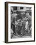 Man Fixing Basket on Bicycle as Children Watch Attentively-Nina Leen-Framed Photographic Print
