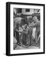 Man Fixing Basket on Bicycle as Children Watch Attentively-Nina Leen-Framed Photographic Print