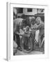 Man Fixing Basket on Bicycle as Children Watch Attentively-Nina Leen-Framed Photographic Print