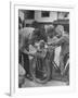 Man Fixing Basket on Bicycle as Children Watch Attentively-Nina Leen-Framed Photographic Print