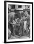 Man Fixing Basket on Bicycle as Children Watch Attentively-Nina Leen-Framed Photographic Print