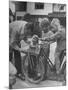 Man Fixing Basket on Bicycle as Children Watch Attentively-Nina Leen-Mounted Photographic Print
