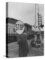 Man Holding Stop Sign by Hand While Automatic Gate Is Being Repaired-null-Stretched Canvas