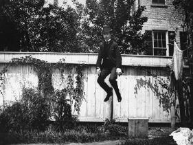 'Man in a Suit and Bowler Hat Jumping in the Air in a Backyard in ...