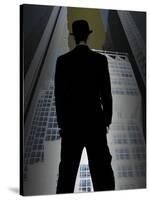 Man in Suit and Bowler Hat Standing in Front of Skyscraper-null-Stretched Canvas