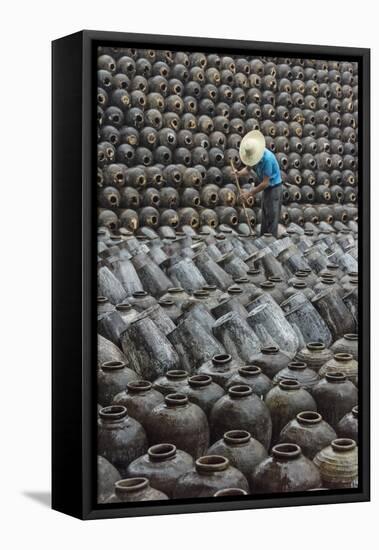 Man in the middle of big pile of wine jars stacked up at a local rice winery, Wuxi, China-Keren Su-Framed Stretched Canvas