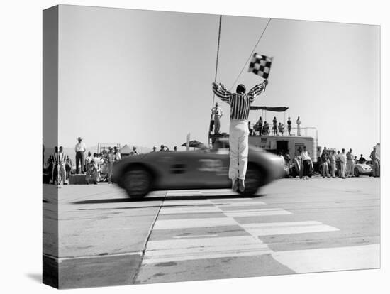 Man jumping waving checkered flag-H^ Armstrong Roberts-Stretched Canvas