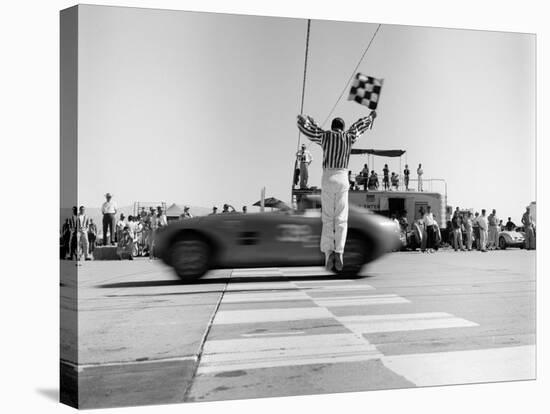 Man jumping waving checkered flag-H^ Armstrong Roberts-Stretched Canvas