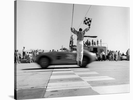 Man jumping waving checkered flag-H^ Armstrong Roberts-Stretched Canvas