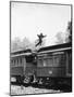 Man Leaping across the Roof of Railroad Cars-null-Mounted Photo