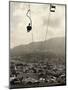 Man Riding Chair Lift Above Town-Jerry Cooke-Mounted Photographic Print