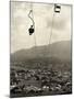 Man Riding Chair Lift Above Town-Jerry Cooke-Mounted Photographic Print