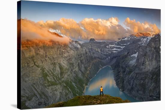 Man standing on rocks looking at clouds at sunset over lake Limmernsee, aerial view-Roberto Moiola-Stretched Canvas