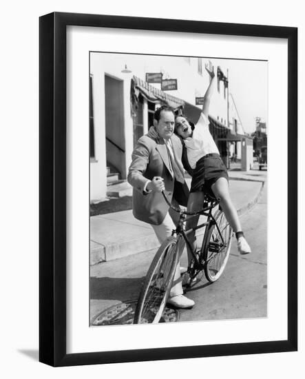 Man Trying to Balance an Exuberant Woman on a Bicycle-null-Framed Photo