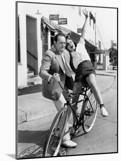 Man Trying to Balance an Exuberant Woman on a Bicycle-null-Mounted Photo