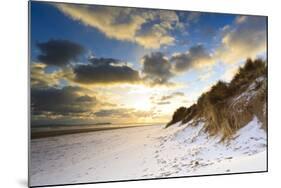 Man Walks Dog on Snow Covered Bamburgh Beach at Dawn with View to Farne Islands-Eleanor-Mounted Photographic Print