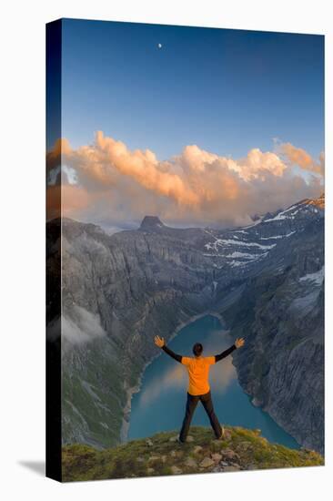 Man with outstretched arms enjoying sunset over lake Limmernsee standing on top of rocks-Roberto Moiola-Stretched Canvas