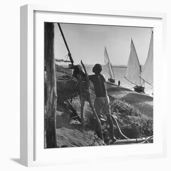 Man Working with Irrigation System as Sailboats Sit at Edge of Nile River at Wadi Halfa-null-Framed Photographic Print