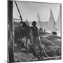 Man Working with Irrigation System as Sailboats Sit at Edge of Nile River at Wadi Halfa-null-Mounted Photographic Print