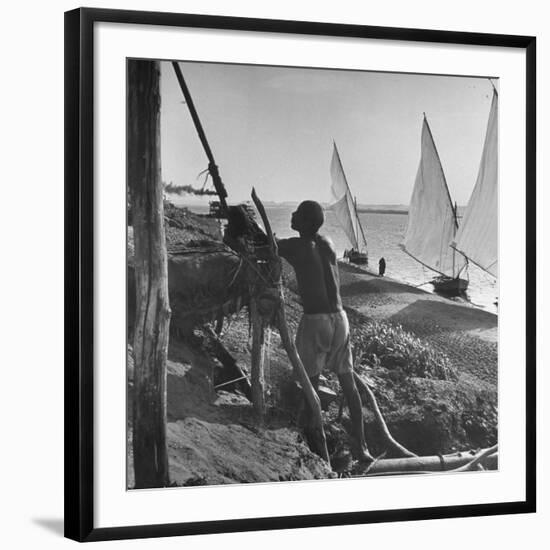 Man Working with Irrigation System as Sailboats Sit at Edge of Nile River at Wadi Halfa-null-Framed Photographic Print