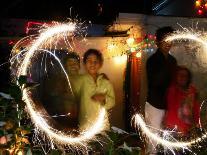 A Woman Lights Earthen Lamps as Children Ignite Firecrackers in New Delhi-Manish Swarup-Stretched Canvas