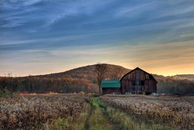 Sun Begins to Rise over a Rustic Old Barn.