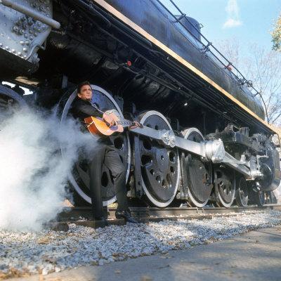 Country/Western Singer Johnny Cash W. Guitar by Wheels of a Steam Train