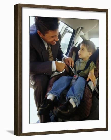 Mid Adult Man Strapping His Son into a Car-null-Framed Premium Photographic Print