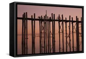 Monk walking at sunrise over the lake near wooden footbridge. Taungthaman Lake, Myanmar.-Michele Niles-Framed Stretched Canvas