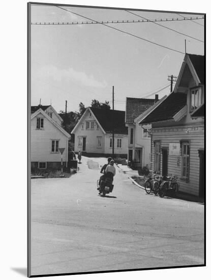 Motorcycle Going Down Street in Small Town-null-Mounted Photographic Print