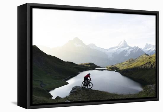 Mountain biker riding downhill at Bachalpsee lake at dawn, Grindelwald, Bernese Oberland-Roberto Moiola-Framed Stretched Canvas