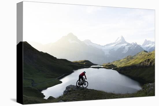Mountain biker riding downhill at Bachalpsee lake at dawn, Grindelwald, Bernese Oberland-Roberto Moiola-Stretched Canvas