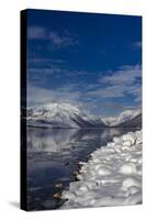Mountains reflect in wintry Lake McDonald in Glacier National Park, Montana, USA-Chuck Haney-Stretched Canvas
