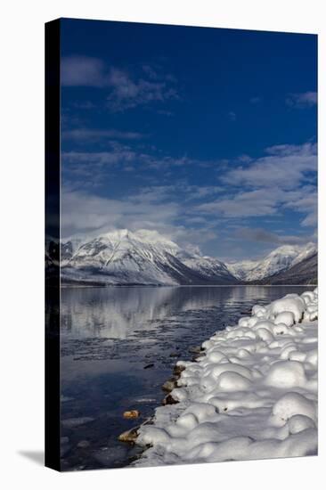 Mountains reflect in wintry Lake McDonald in Glacier National Park, Montana, USA-Chuck Haney-Stretched Canvas