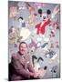 Movie Studio Head Walt Disney Sitting in Front of Backdrop Filled with Disney Creations-Alfred Eisenstaedt-Mounted Premium Photographic Print