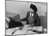 Mrs Teruko Kiyomura, bookkeeper, seated at desk, operating an adding machine while reading a ledger-Ansel Adams-Mounted Photographic Print