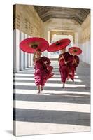 Myanmar, Mandalay Division, Bagan. Three Novice Monks Running with Red Umbrellas in a Walkway (Mr)-Matteo Colombo-Stretched Canvas