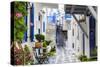 Narrow street, whitewashed buildings with blue paint work, flowers, Mykonos Town (Chora), Mykonos,-Eleanor Scriven-Stretched Canvas