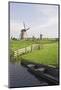 Netherlands, Kinderdijk. Windmills and boat next to canal.-Jaynes Gallery-Mounted Photographic Print